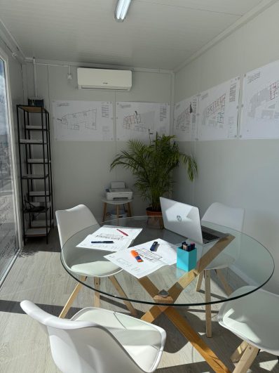 Interior de la caseta de ventas de Ermita 44 con planos de viviendas y zona de atención al cliente